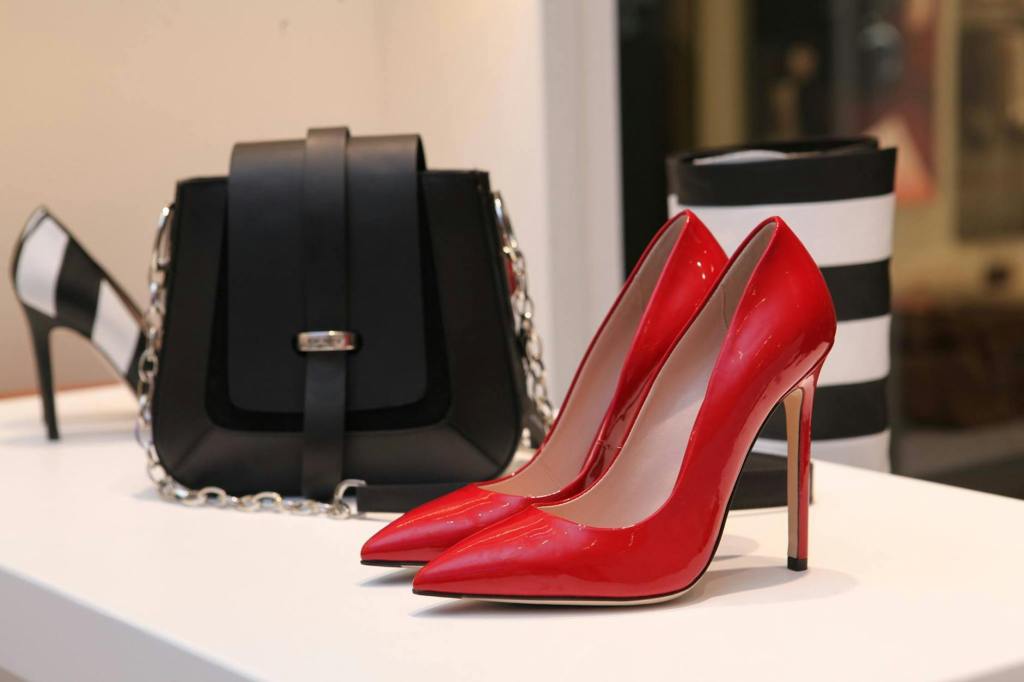 Black Leather Handbag Alongside Red Stiletto Shoes